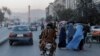 Sekelompok perempuan yang mengenakan burqa tampak menyeberang jalan saat anggota pasukan Taliban bergerak melewati mereka di Kabul, pada 9 Oktober 2021. (Foto: Reuters/Jorge Silva)