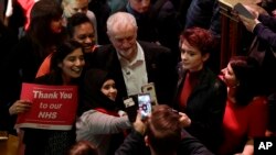 The leader of Britain's opposition Labour party Jeremy Corbyn poses with supporters after his speech at a rally to demand the government introduce an emergency budget for the National Health Service (NHS) to end a winter crisis, at Methodist Central Hall in London, Thursday, Jan. 25, 2018.