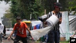 ARCHIVO - La gente drena el agua de sus tiendas de campaña después de las fuertes lluvias en un campamento de migrantes en las vías del tren de Vallejo en la Ciudad de México, el jueves 18 de julio de 2024.