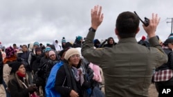 La peruana Julia Paredes, al centro, escucha las instrucciones de un agente de la patrulla fronteriza junto a otros solicitantes de asilo, mientras esperan a ser procesados tras cruzar la cercana frontera con México, el jueves 25 de abril de 2024, en Boulevard, California. 