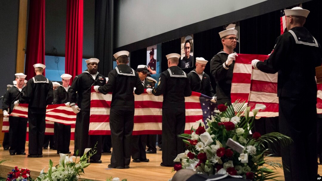 In this photo, released by the U.S. Navy, sailors fold seven U.S. flags during a memorial service in Yokosuka, south of Tokyo, Japan, June 27, 2017, for seven sailors who were killed while serving on the USS Fitzgerald when it collided with a merchant ship off Japan, June 17, 2017.