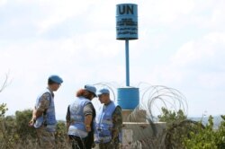 FILE - Members of the unarmed United Nations Truce Supervision Organization stand near a U.N. "Blue Line" notification, in the southern Lebanese town of Ramyah, Sept. 9, 2019.