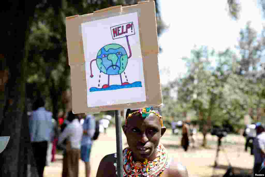 An environmental activist dressed in traditional wear holds a sign as he takes part in the Climate strike protest calling for action on climate change, in Nairobi, Kenya, September 20, 2019.