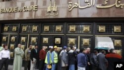 ژماره‌ک هاوڵاتی له‌ به‌رده‌می بانکێـکی قاهیره‌ی پایته‌ختدا ڕیزیان به‌سـتووه‌، یه‌کشه‌ممه‌ 6 ی دووی 2011