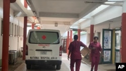 FILE — Nigerian health workers walk past an ambulance parked outside a ward of the national hospital in Abuja, on July 26, 2023. 