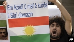 Seorang Kurdi dalam sebuah protes anti Presiden Suriah Assad di depan Kedubes Suriah di Lebanon (23/10/2011). Spanduk yang dibawanya berbunyi "Kami ingin kebebasan dan hak untuk orang Kurdi di Suriah".