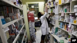 FILE - An Iranian pharmacist arranges medicine on shelves at a pharmacy in central Tehran, Iran, Dec. 11, 2012. The strength of the U.S. dollar and concerns that the U.S. will again impose tough economic sanctions have prompted the price of pharmaceuticals to jump.