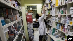 FILE - An Iranian pharmacist arranges medicine on shelves at a pharmacy in central Tehran, Iran, Dec. 11, 2012. The strength of the U.S. dollar and concerns that the U.S. will again impose tough economic sanctions have prompted the price of pharmaceutical