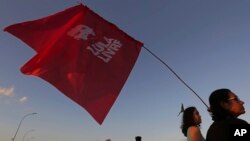 A supporter of Brazil's former President Luiz Inacio Lula da Silva carries a flag with text written in Portuguese that reads "Free Lula" during a protest in front of the headquarters of the Brazilian Supreme Court, in Brasilia, Brazil, July 9, 2018. 