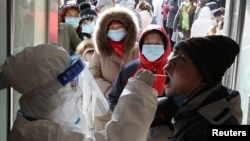 FILE - A medical worker in protective suit collects a swab from a resident during a mass nucleic acid testing following a recent coronavirus disease outbreak in Shijiazhuang, Hebei province, China, Jan. 6, 2021. 