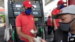 Un cliente paga con dólares estadounidenses para abastecer su motocicleta en una gasolinera en Caracas, Venezuela, el 1 de junio de 2020.