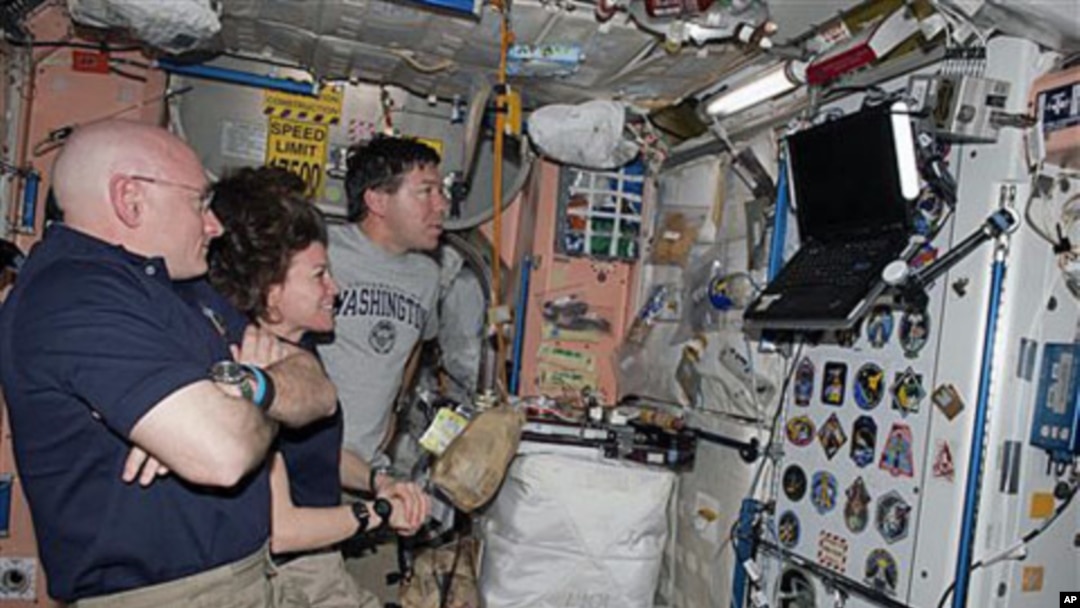 Astronauts Scott Kelly, left, Expedition 26 commander; Cady Coleman, center, Expedition 26 flight engineer; and Michael Barratt, STS-133 mission specialist, watch a monitor in the International Space Station while space shuttle Discovery remains docked wi