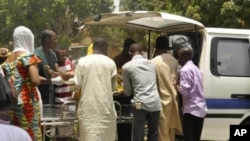 Local officials remove the body of a victim from the back of a bus, in front of Aminu Kano teaching hospital in Nigeria's northern city of Kano, April 29, 2012. 