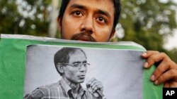 Seorang mahasiswa mengangkat potret Profesor A.F.M. Rezaul Karim Siddique dalam protes menentang pembunuhan. Dhaka, Bangladesh.