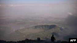 Des volcanologues et des gardes forestiers congolais du parc national des Virunga regardent la vallée du haut du volcan Nyiragongo, au nord de Goma, la capitale provinciale du Nord-Kivu, le 11 juin 2021.