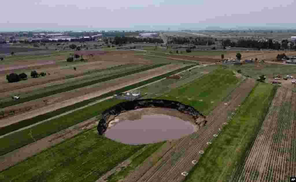 A water-filled sinkhole increases in size at a farming field in Zacatapec, on the outskirts of Puebla, Mexico.