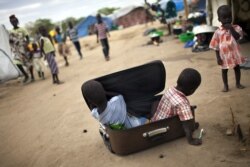 FILE - Children play with a suitcase in a displaced persons camp for the Nuer ethnic group inside the UNMISS compound in Bor, South Sudan, Feb. 27, 2014.
