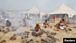 FILE - Hindu holy men offer prayers while sitting inside circles of burning "Upale" (or dried cow dung cakes) on the occasion to mark the Basant or spring festival, on the banks of river Ganga in Allahabad, India, Feb. 1, 2017.