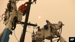 FILE - Pacific Gas & Electric crews work to restore power lines in Paradise, Calif., Nov. 9, 2018.