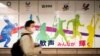 فیس ماسک پہنے ہوئے ایک شخص شن جوکو سٹی ہال سے گزر رہا ہے جہاں پس منظر میں اولمپکس کا ایک پوسٹر لگا ہے۔ 29 جنوری 2021