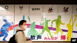 FILE - A man wearing a face mask visits the Shinjuku City Hall promoting the Tokyo 2020 Olympics, rescheduled for this summer in Tokyo, Jan. 29, 2021.