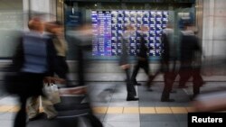 Passersby walk past stock quotation board outside brokerage, Tokyo, Dec. 4, 2013.