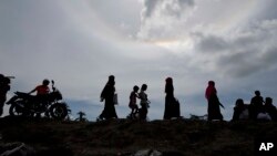 Bangladeshi women, center, walk towards newly arrived Rohingya Muslims from Myanmar, far right, in Teknaf, Bangladesh, Oct. 02, 2017.