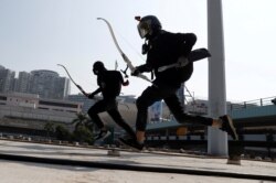 Protesters with bows practice running away from riot police, on the roof of a bus shelter near the Cross Harbour Tunnel, which was blocked after demonstrators occupied the nearby Hong Kong Polytechnic University, in Hong Kong, Nov. 15, 2019.