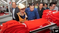 FILE: Prime Minister Hun Sen, center, leans over a garment worker during a visit to a factory outside of Phnom Penh, Cambodia, Aug. 30, 2017.