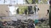 FILE – Soldiers stand near the wreckage of a car bomb that was detonated at the gates of a government office complex in the capital Mogadishu, April 14, 2015.