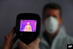 FILE - An infrared camera is shown scanning a person for elevated body temperature at a General Motors plant in Warren, Michigan, April 23, 2020.