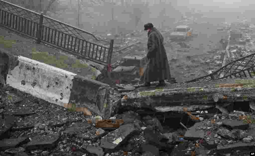 An elderly woman walks across a destroyed bridge, the scene of heavy fighting in Donetsk, Ukraine, March 1, 2015.