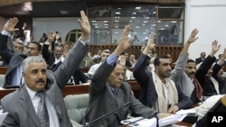 Members of Yemen's Parliament raise their hands to vote in favor of a law granting immunity to outgoing President Ali Abdullah Saleh over the killing of protesters, in Sana'a, January 21, 2012.