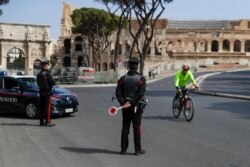 A cyclist rides past Carabinieri police officers at a roadblock near the Colosseum, in downtown Rome, April 3, 2021. Italy went into lockdown on Easter weekend in its effort to battle the COVID-19 pandemic.