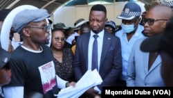 Protest organizer Setlhomo Tshwanelang, left, presents a petition to Minister of Trade Tiroeaone Ntsima, in Gaborone, Botswana, Nov. 18, 2024.