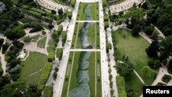 Lukisan raksasa "Beyond Walls" karya pelukis jalanan Perancis, Saype. Lukisan yang menggunakan cat semprot menggambarkan tangan yang berpegangan terbentang di halaman Champs de Mars di Paris, Perancis, 14 Juni 2019. (Foto: Reuters)