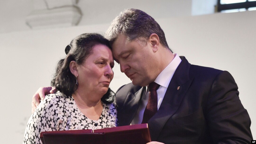 Ukrainian President Petro Poroshenko, right, presents a Hero of Ukraine award to a relative of an activist killed a year ago during mass protests, at the award ceremony in Kyiv, Feb. 20, 2015.