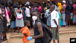FILE: A man wearing a mask is seen near a food queue in Harare, Zimbabwe, March 25, 2020. 