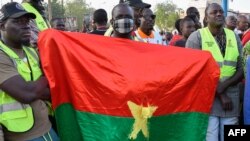 FILE - Supporters of the Alliance Of Sahel States (AES) hold up a Burkina Faso Flag as they celebrate Mali, Burkina Faso and Niger leaving the Economic Community of West African States (ECOWAS) in Niamey on January 28, 2024.