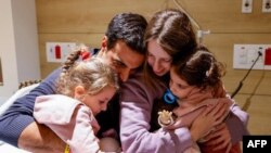 An image distributed by the Schneider Children Medical Centre shows Yoni Asher being reunited with his children Aviv, 2.5 years old, her sister Raz, 4.5 years old, and his wife Doron, on November 25, 2023. 