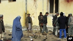 Afghans stand at the site of a suicide attack in Emam Saheb district of Kunduz province February 21, 2011