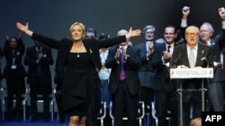 Marin Le Pen. O'ng tomonda uning otasi, taniqli millatchi siyosatchi, 2002 yilda prezidentlik uchun bellashgan Jan-Mari Le Pen. Ikkala siyosatchi immigratsiya, Yevropa Ittifoqi va musulmonlarga qarshi g'oyalarni ilgari suradi.