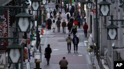 People wearing protective masks to help curb the spread of the coronavirus walk along a shopping street in Tokyo, Jan. 11, 2021. 