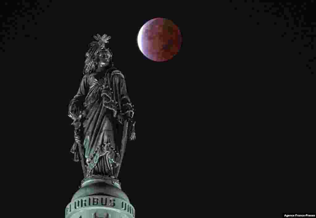 The moon, with a partial lunar eclipse, is seen behind the Statue of Freedom, on Capitol Hill in Washington, DC early on Nov. 19, 2021.