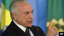 FILE - Brazil's President Michel Temer speaks during a ceremony at the Planalto Presidential Palace, in Brasilia, June 26, 2017. Temer is expressing defiance in the face of possible corruption charges.