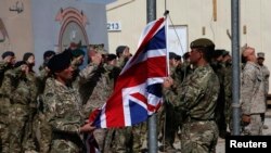 FILE - British troops lower the Union flag during a ceremony marking the end of operations for U.S. Marines and British combat troops in Helmand, Afghanistan, Oct. 26, 2014. 