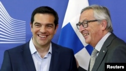 Greek Prime Minister Alexis Tsipras (L) is welcomed by European Commission President Jean-Claude Juncker ahead of a meeting at the EU Commission headquarters in Brussels, June 3, 2015. 