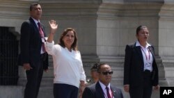 Rodeada por seguridad, la presidenta peruana Dina Boluarte saluda a la prensa afuera del palacio de gobierno cuando el primer ministro Alberto Otarola sale de Lima, Perú, el martes 10 de enero de 2023.