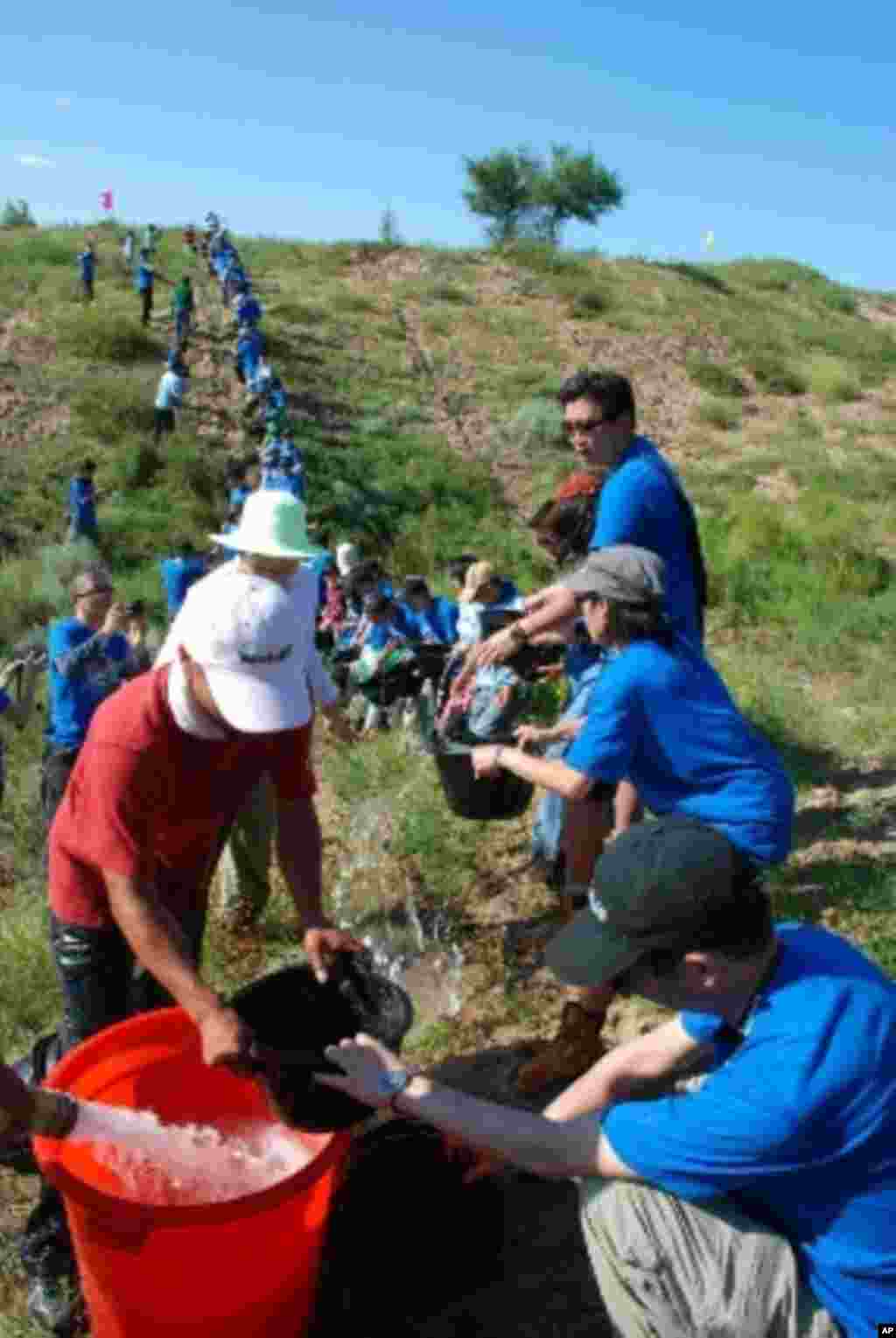 義工們列隊分工合作灌溉剛種下的樹苗