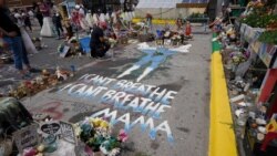 FILE - A woman kneels to weep at the spot where George Floyd was killed, as people gather during the sentencing hearing of former Minneapolis police officer Derek Chauvin for Floyd's murder, in Minneapolis, June 25, 2021.